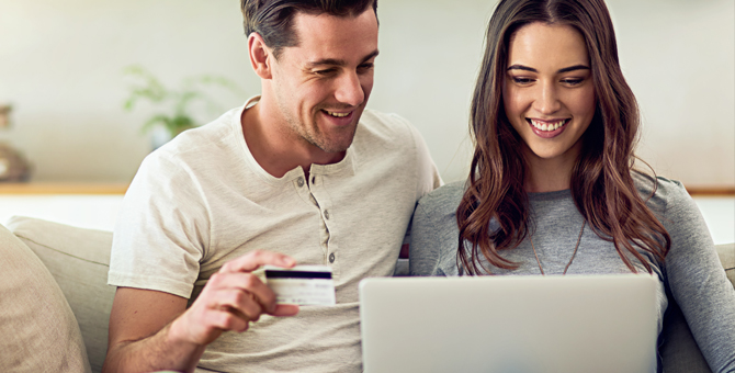 Photo of couple using a credit card for online shopping